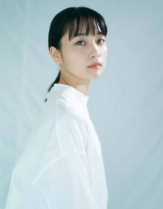 Woman with black hair in a white shirt looking over her shoulder