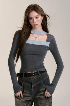 Woman with long brown hair wearing a gray long-sleeve top and distressed jeans