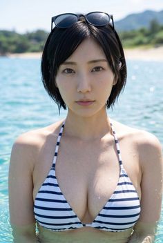 Woman in a striped bikini with sunglasses on her head, standing in clear water