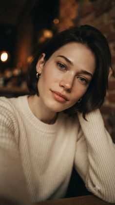 Woman with short hair and freckles wearing a white sweater, looking at the camera