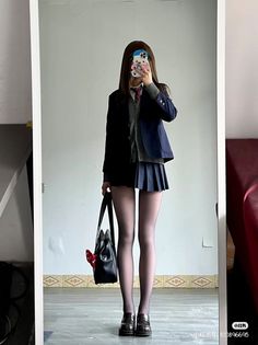 Person in a school uniform and black tights taking a mirror selfie