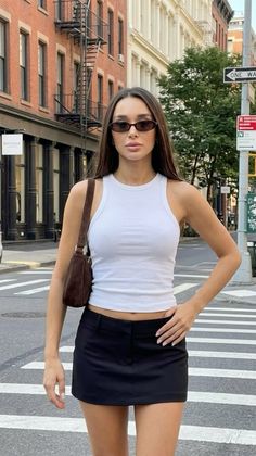 Woman in a white tank top and black mini skirt on a city street