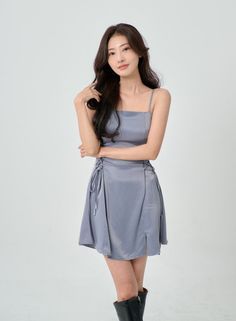 Woman with long dark hair wearing a light blue mini dress and black boots