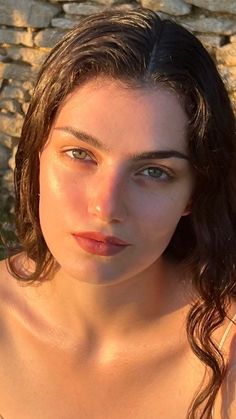 Woman with long dark hair and green eyes in warm golden hour light