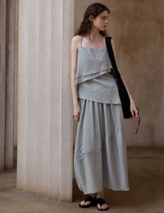 Woman with long hair wearing a layered top and maxi skirt indoors