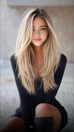 Woman with long blonde hair wearing a black top, looking directly at the viewer