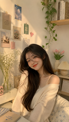 Woman with long dark hair wearing an off-shoulder sweater in soft, warm lighting