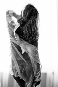 Woman with long hair in a sheer shirt, seen from behind with strong backlight