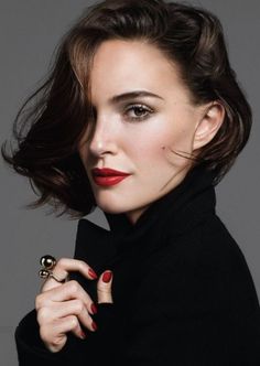Woman with short brown hair, red lipstick, and a black coat with a gold ring