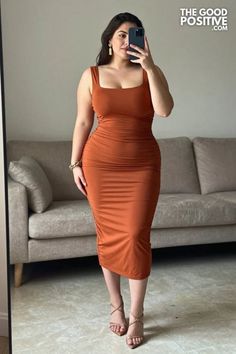 Woman in a rust-colored bodycon dress taking a mirror selfie