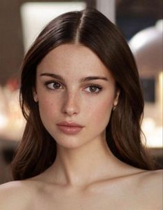 Woman with long brown hair and freckles looking directly at the viewer