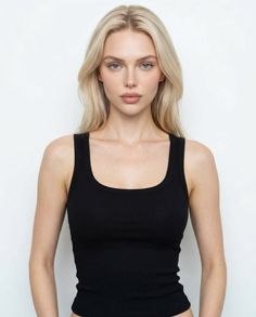 Woman with blonde hair wearing a black tank top against a white background