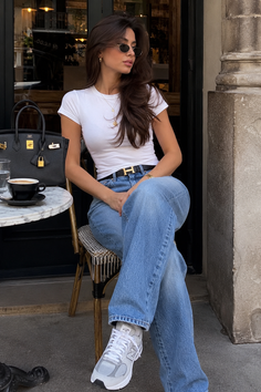 Woman with long hair and sunglasses sitting at an outdoor cafe