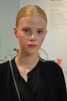 Blonde woman with a ponytail wearing a black shirt and silver chain indoors