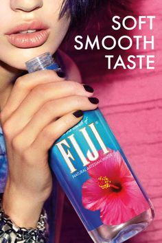 Woman holding a Fiji water bottle against a pink background