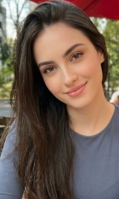 Woman with long brown hair smiling outdoors with soft lighting