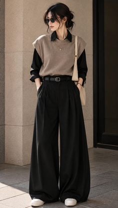 Woman in wide leg pants, a black shirt, and a sleeveless sweater with sunglasses