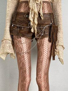Person wearing brown fishnet stockings, lace top, and leather shorts with a silver chain