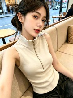 Woman in a sleeveless top with a zipper sitting on a couch in a cafe
