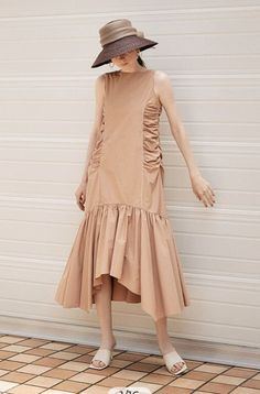 Woman in a sleeveless midi dress and straw hat standing outdoors