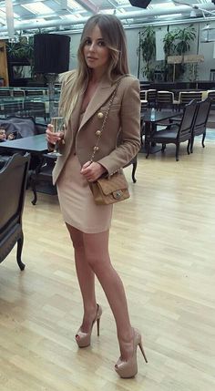Woman in a blazer and mini dress holding a champagne glass indoors