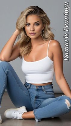 Woman with blonde hair wearing a white tank top and blue jeans in a studio