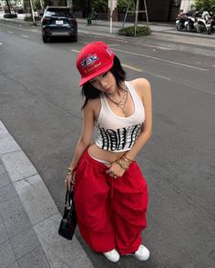 Woman in a red cap and baggy pants posing on a street