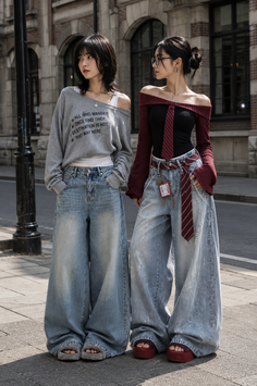 Two women in wide leg jeans and off-shoulder tops standing on a city street