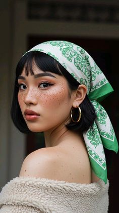 Woman with a green bandana and freckles looking over her shoulder