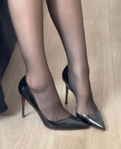 Legs in black pantyhose and shiny high heels on a wooden floor