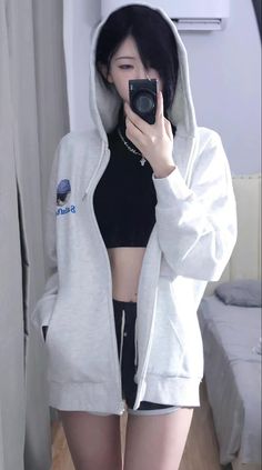 Person in a white hoodie and black crop top taking a mirror selfie