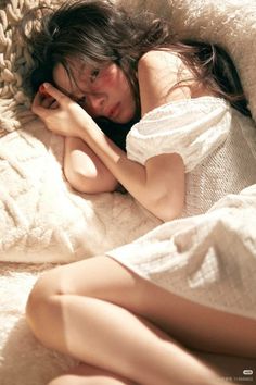 Woman with long hair in a white dress lying on a textured blanket