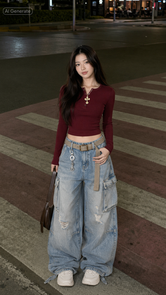 Woman in a maroon crop top and baggy cargo pants standing on a street at night