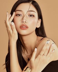 Woman with long black hair and jewelry posing in a studio