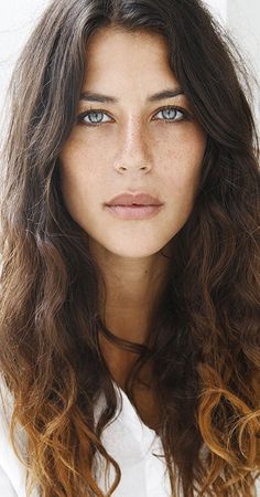 Close-up portrait of a woman with long wavy hair and blue eyes