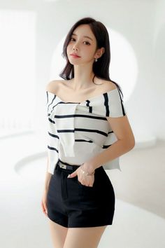 Woman in a striped off-shoulder top and black shorts indoors
