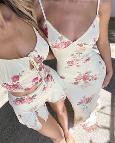Two women in matching floral print outfits, one in a dress and one in a crop top and skirt