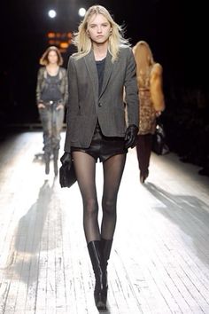 Blonde model in a blazer, leather shorts, and tights walking on a runway