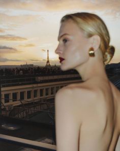 Woman with blonde hair and red lipstick on a rooftop overlooking the Eiffel Tower at sunset