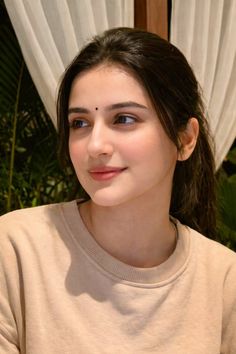 Woman with a bindi and ponytail wearing a beige sweatshirt outdoors