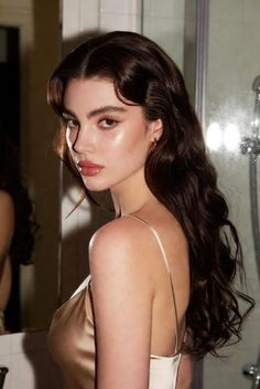Woman with long wavy hair in a satin dress looking over her shoulder