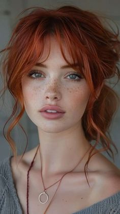 Woman with red hair and freckles wearing a simple necklace