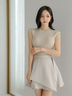 Woman with black hair wearing a ribbed top and mini skirt indoors