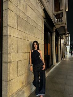 Woman in a denim halter top and wide leg jeans on a street at night