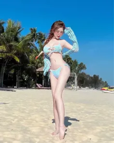 Woman in a light blue crochet bikini and long sleeves posing on a sunny beach