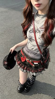 Person with red highlights and plaid skirt holding a hat outdoors