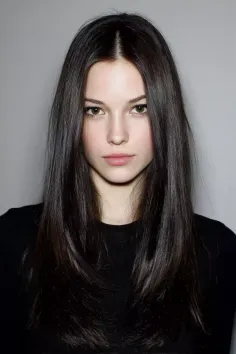 Woman with long dark hair wearing a black shirt in a studio portrait