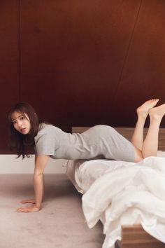 Woman in a gray dress posing on a bed in a bedroom