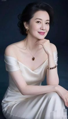 Woman in an off-shoulder dress with jewelry against a dark background
