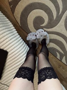 Person wearing black lace-trimmed thigh-high stockings and cute animal slippers